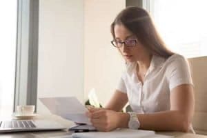 A woman checking a piece of paper with glasses on