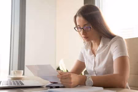 A woman checking a piece of paper with glasses on