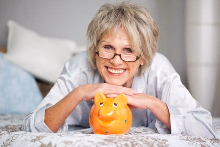 posts-successful-savers - Harold Shepley & Associates, LLC An old lady smiling at the camera leaning on a piggy bank