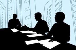 A group of men sitting at a table with a blue background